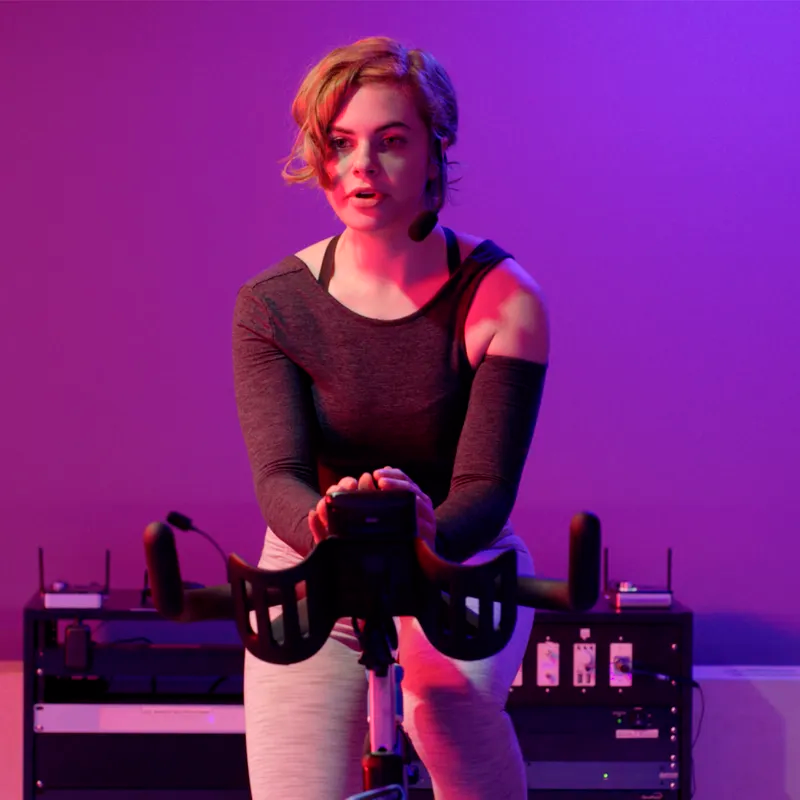 Liikunnanohjaaja spinning-pyörän selässä käyttää Samson AirLine 99m Fitness -headset-mikrofonia