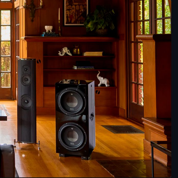 REL 212 Black Label kiiltävä musta subwoofer olohuoneessa, lifestyle-kuva