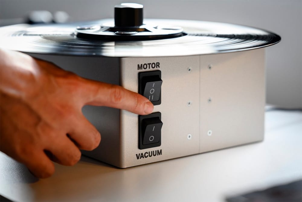 Pro-Ject VC-E Mini äänilevyjen pesukone käytössä, käsi painaa moottorikytkintä laitteen etupaneelissa.