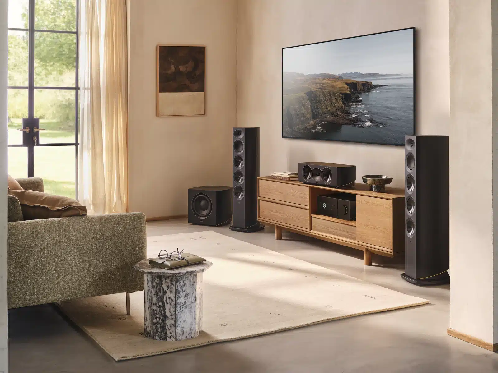Arcam Radia R35C -keskikaiutin television alla olohuoneen Radia-kotiteatterissa, lattiakaiuttimien välissä.